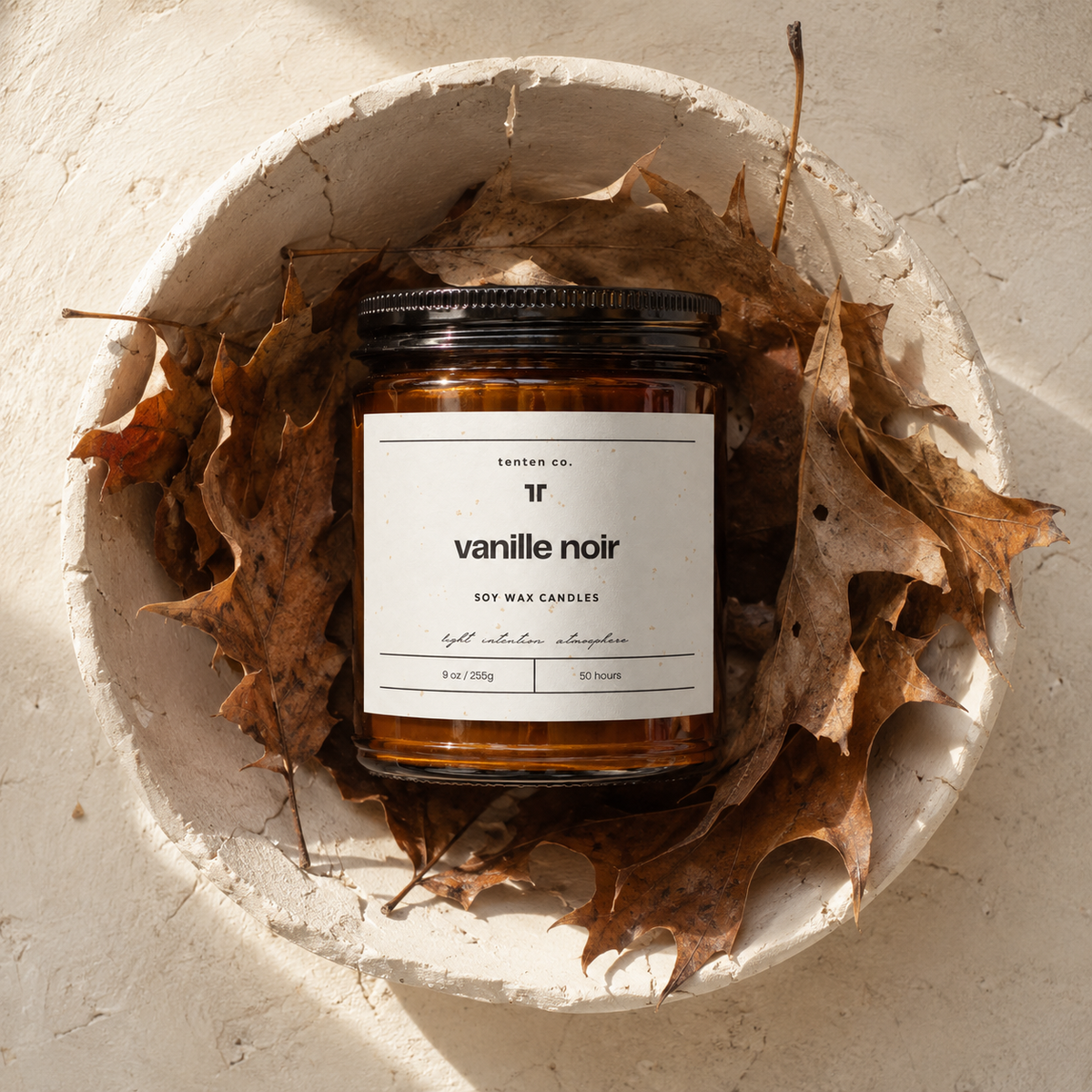 TenTen Vanille Noir 255g candle in a raw plaster bowl with dried leaves